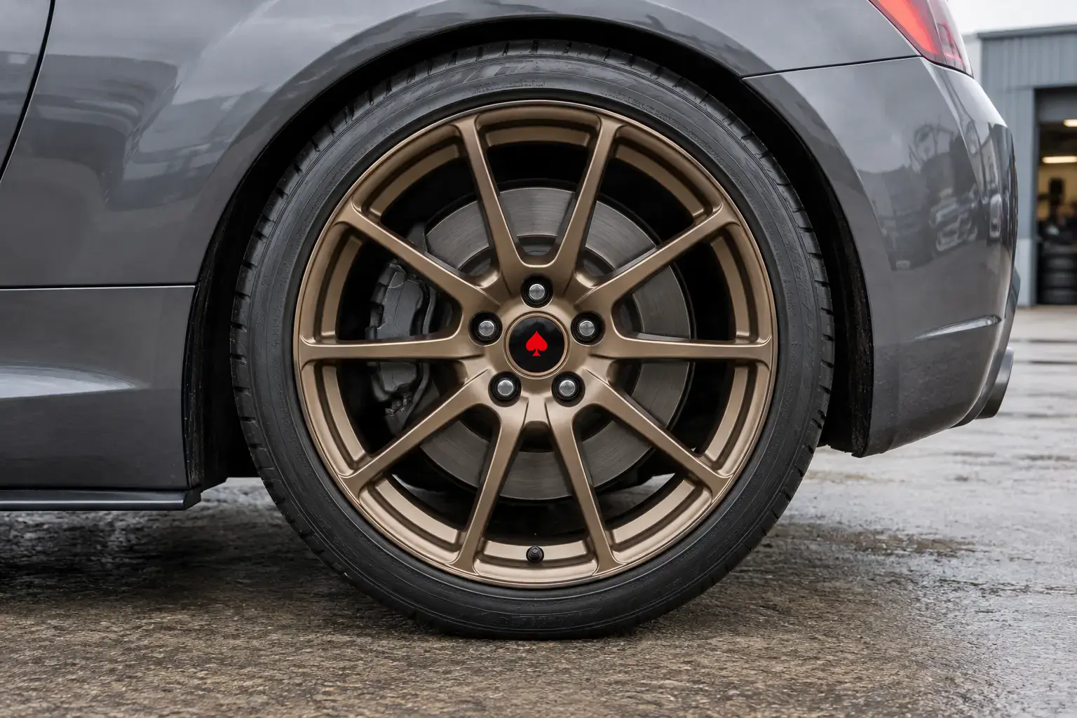 Illustrative bronze alloy wheel on a grey car